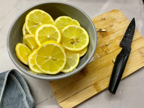 Pieces of lemon lie on a gray round plate standing on a wooden board. High quality photo