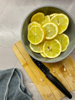 Pieces of lemon lie on a gray round plate standing on a wooden board. High quality photo
