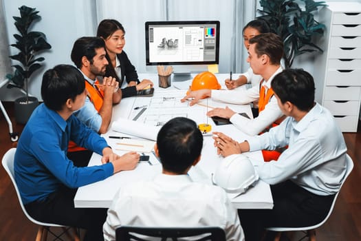 Diverse group of civil engineer and client working together on architectural project, reviewing construction plan and building blueprint at meeting table. Prudent