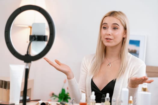 Young woman making beauty and cosmetic tutorial video content for social media. Beauty blogger smiles to camera while showing how to beauty care to audience or followers. Blithe