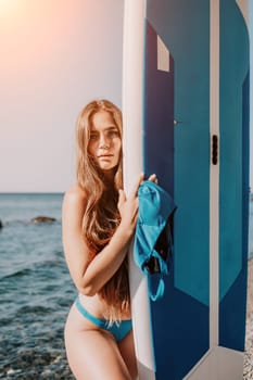 Close up shot of beautiful young caucasian woman with black hair and freckles looking at camera and smiling. Cute woman portrait in a pink bikini posing on a volcanic rock high above the sea