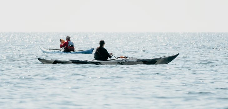 Happy smiling woman in kayak on ocean, paddling with wooden oar. Calm sea water and horizon in background