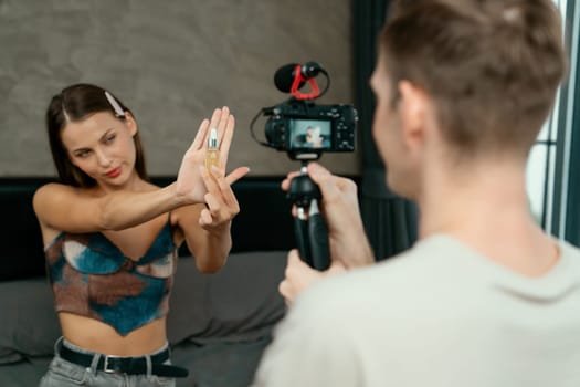 Man filming video on young woman making beauty and cosmetic tutorial video content for social media. Beauty blogger smiles to camera while showing how to beauty care to audience or follower. Unveiling