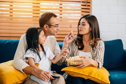 A joyful family enjoys movie time with popcorn in the living room. The father mother son daughter and schoolgirl create cherished moments filled with smiles and relaxation during their quality time.