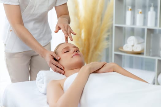 Caucasian woman enjoying relaxing anti-stress head massage and pampering facial beauty skin recreation leisure in dayspa modern light ambient at luxury resort or hotel spa salon. Quiescent