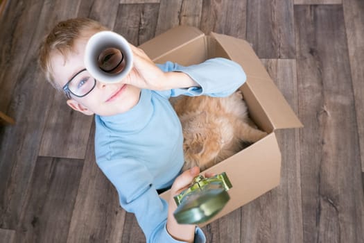 A small child, a boy, plays a pirate with a cat sitting in a box. Children's games in the children's room. Real friendship