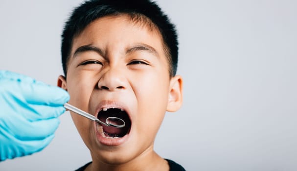 In a pediatric dentist's clinic a doctor examines a child's mouth post removal of loose milk tooth. Dental tools help in detailed examination process. Doctor uses mouth mirror to checking teeth cavity