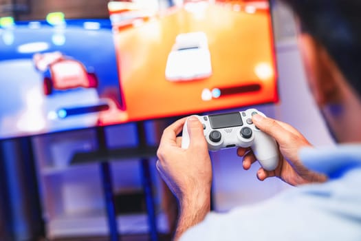 Close up of photo of holding joystick with two hands by gaming streamer playing car racing competition of video game on blurred screen. Concept of lifestyles gamer on weekend with friend. Sellable.