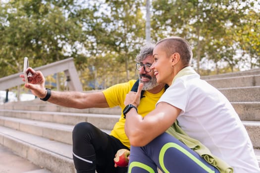 senior sports man taking a selfie photo with his personal trainer while they rest after training, concept of technology and healthy lifestyle