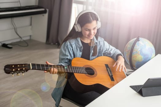 Beautiful young girl with long hair playing the guitar, sitting at home . studying the melody. Home leisure, hobbies, self-development. High quality photo