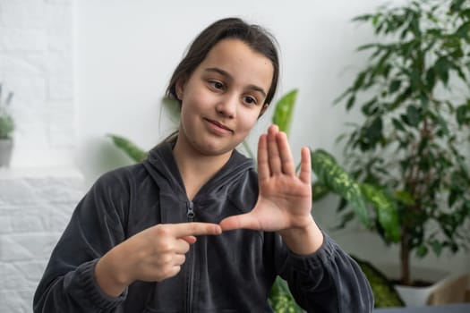 Cute deaf mute girl using sign language on light background.
