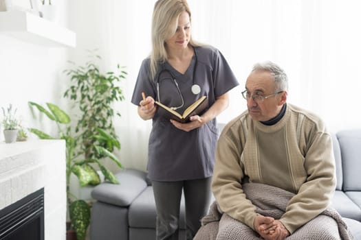 Kind female doctor embracing encouraging senior male patient in hospital. Happy healthy older man and his physician enjoying talking at nursing home. Elderly medical health care concept