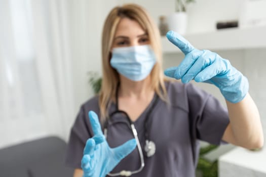 A female doctor wearing rubber gloves shows a gesture of holding something