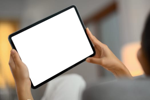 Closeup woman using digital tablet while lying on couch at home.