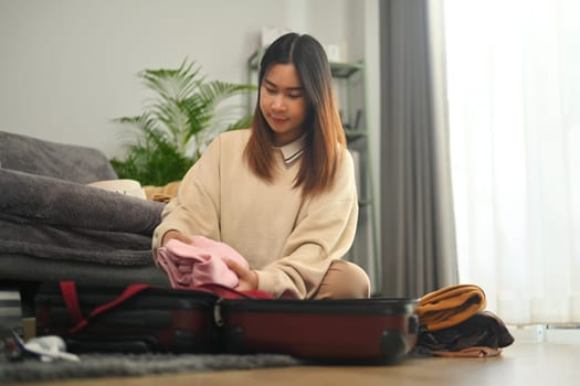 Young woman packing luggage in suitcase for a vacation trip. Travel and lifestyle concept.