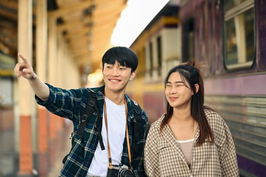 Happy young couple walking at railroad station platform. Travel and vacations concept.