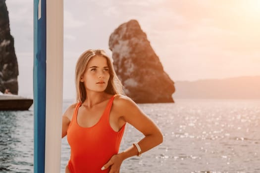 Close up shot of beautiful young caucasian woman with black hair and freckles looking at camera and smiling. Cute woman portrait in a pink bikini posing on a volcanic rock high above the sea