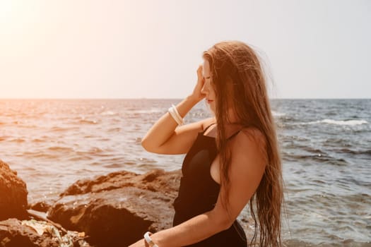 Woman travel sea. Young Happy woman in a long red dress posing on a beach near the sea on background of volcanic rocks, like in Iceland, sharing travel adventure journey