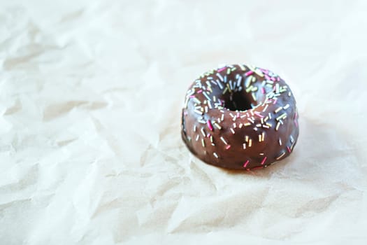 Sweet chocolate donut with sprinkles on light background, Delicious colorful chocolate donut. Copy space