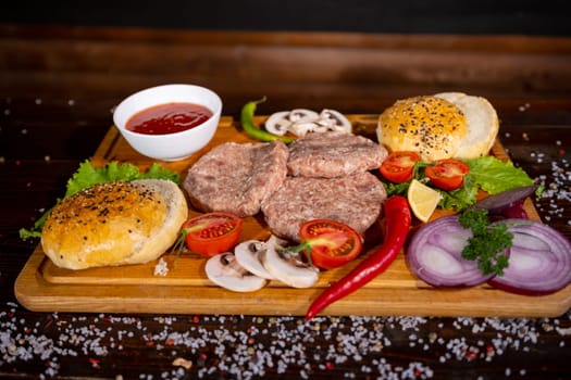 Process of cooking burgers. Cropeed view of chef hands in black gloves with prepared cheeseburger, variety of fillings and ingridients on wooden desk. Catering and Good Quality Fastfood concept.