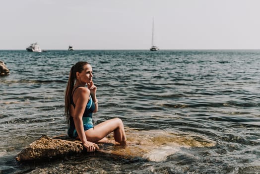 Woman beach vacation photo. A happy tourist in a blue bikini enjoying the scenic view of the sea and volcanic mountains while taking pictures to capture the memories of her travel adventure