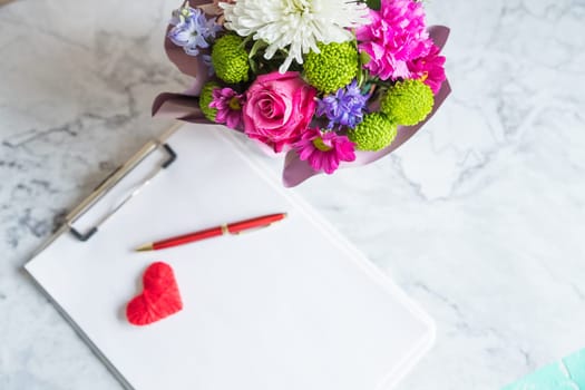Bouquet of red roses and an envelope with a note on a white back