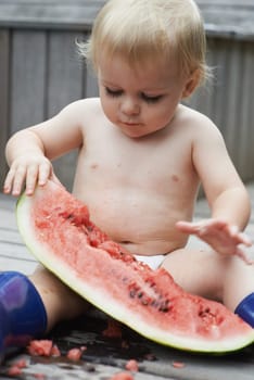 Baby, playing with watermelon and eating, backyard and development with growth, curiosity and home. Toddler, child and infant in garden, alone and childhood for wellness, milestone and coordination.