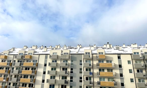 A high-rise building in the city against the background of a blue sky with white clouds. High quality photo