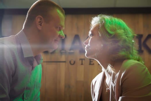 Adult man and woman are conversing on stage in dimly lit room before a performance or interview. The actors, actress, host, journalist, and paparazzi capturing their intimate, secretive conversation