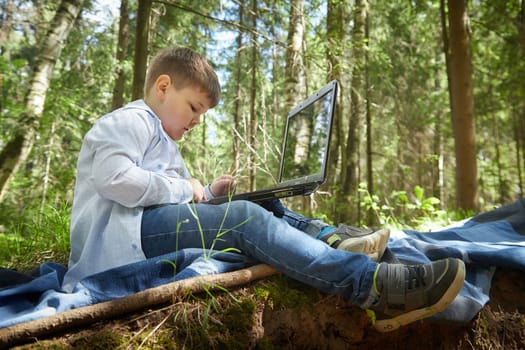 Fat teenage boy in the park with a laptop. Gamer, streamer, blogger, sociopathic programmer working alone in the forest
