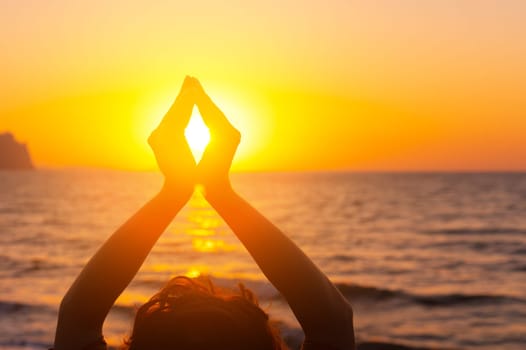 Woman's hands symbolizing prayer and gratitude. Mudra. Yoga concept. Silhouette of female hands on sun background. Beautiful scene.