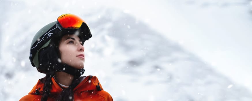 Panoramic photo of a Caucasian young woman in a ski helmet against the backdrop of a snowy landscape.