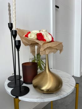 There are candlesticks, an aroma lamp, a candle and a bouquet of roses on a round table. High quality photo