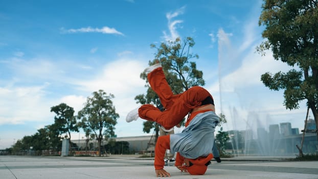 Asian skilled hipster doing freeze pose at camera surrounded by break dancer team near fountain with sky background. Group of handsome people practice b-boy dance. Outdoor sport 2024. Sprightly.