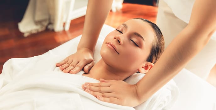 Caucasian woman customer enjoying relaxing anti-stress spa massage and pampering with beauty skin recreation leisure in day light ambient salon spa at luxury resort or hotel. Quiescent