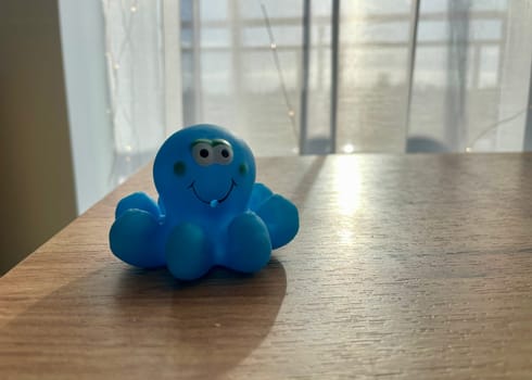 A rubber blue children's toy octopus is illuminated by sunlight in front of the window. High quality photo
