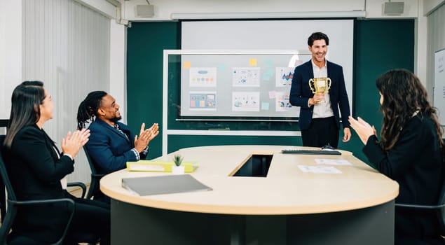 In a meeting room, a triumphant businessman holds an award trophy, surrounded by congratulatory teamwork. This exemplifies success, leadership, and achievement in business management.