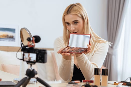 Young woman making beauty and cosmetic tutorial video content for social media. Beauty blogger smiles to camera while showing how to beauty care to audience or followers. Blithe