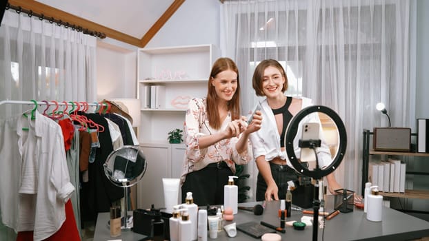 Two women influencer partner shoot live streaming vlog video review skincare for prim social media or blog. Young girl with cosmetic studio lighting for marketing recording session broadcasting online