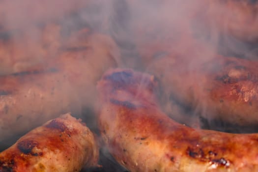 Close up on details of homemade sausages on barbecue grill. Barbecue, grill and food concept.