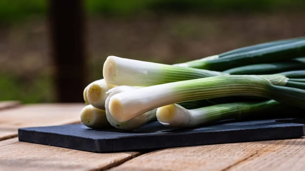 Close up of details of fresh green onions (scallion) on a cutting board isolated.