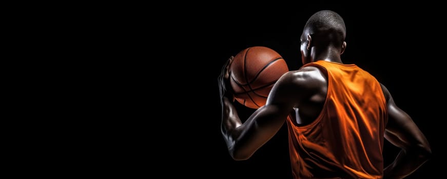 A basketball player stands with his back to the camera, looking over the court with a basketball at his side, exuding focus and readiness before the game.