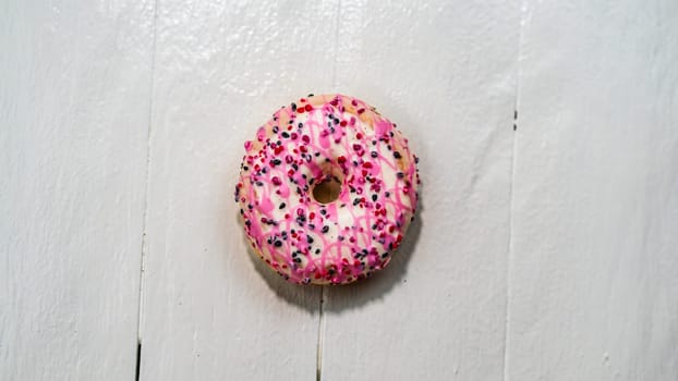 Colorful donuts on white wooden table. Sweet icing sugar food with glazed sprinkles, doughnut with frosting. Top view with copy space