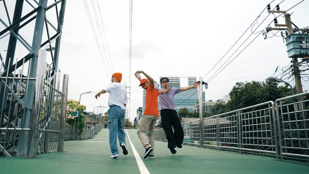 Back view of skilled hipster walking while turn around and looking at camera. Group of professional break dancer pose at camera and perform street dance foot step. Outdoor sport 2024. Sprightly.