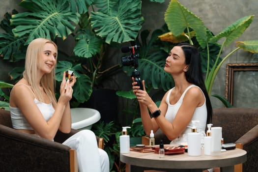 Two beautiful content creator making natural beauty and cosmetic tutorial on green plant garden video. Beauty blogger showing how to beauty care to social medial audience using selfie stick . Blithe