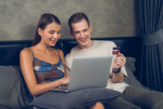 Young couple sit in the home bedroom using online payment app and digital wallet on smartphone to pay with credit card. E commerce shopping and modern purchasing via mobile internet. Unveiling