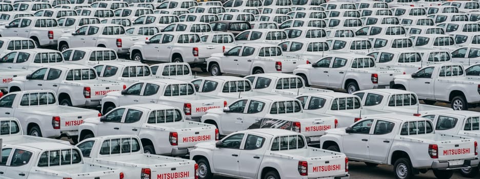 Lamchabang, Thailand - July 02, 2023 Amidst a car factory's cloudy day, rows of new sedans are parked in a crowded distribution center. the bustling parking, showcasing modern industry.