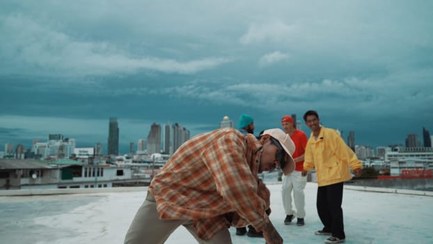 Professional asian street dancer practice B boy dance while multicultural friends at roof top. Young modern dancing group doing hip hop movement. Style,fashion,action. Outdoor sport 2024. Endeavor.