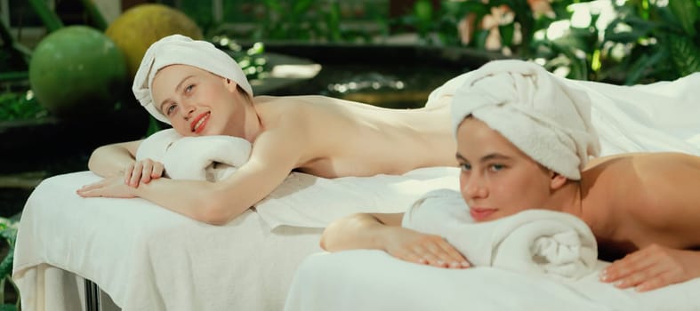 A portrait of a couple of a beautiful young caucasian woman with white towel rest on comfortable spa bed with relaxation while having body massage with professional masseur at spa salon.Tranquility.