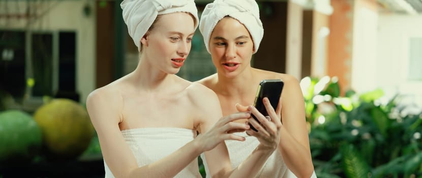 Couple of young beautiful women with beautiful skin in white towel taking a photo together at outdoor surrounded by peaceful natural environment. Beauty and healthy spa concept. Tranquility.